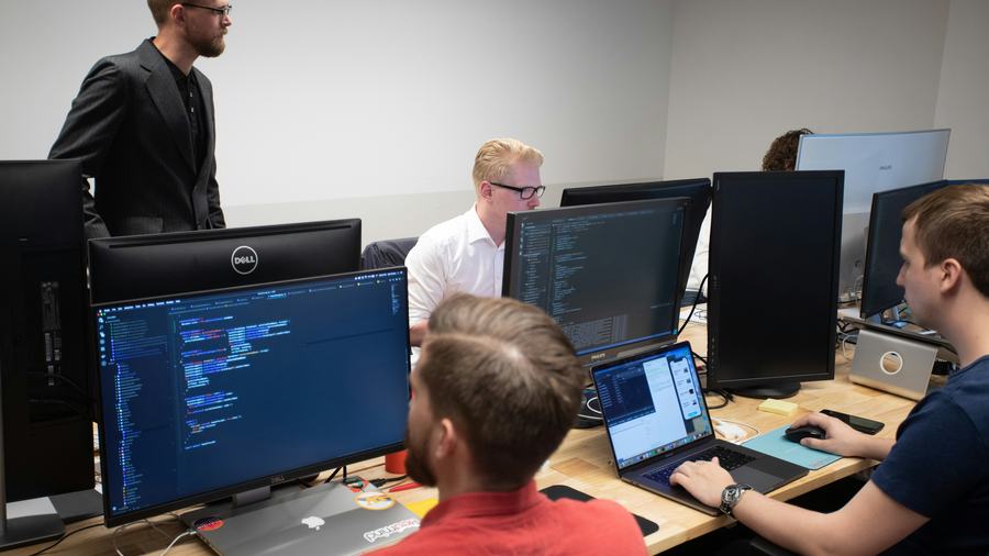 Instructor guiding IT students at their workstations