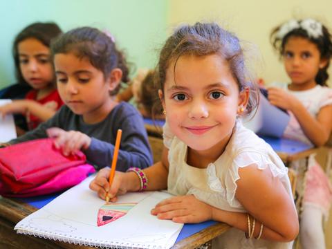 Smiling girl drawing at her desk