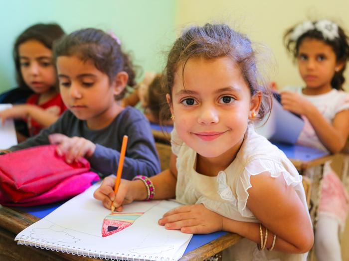 Smiling girl drawing at her desk